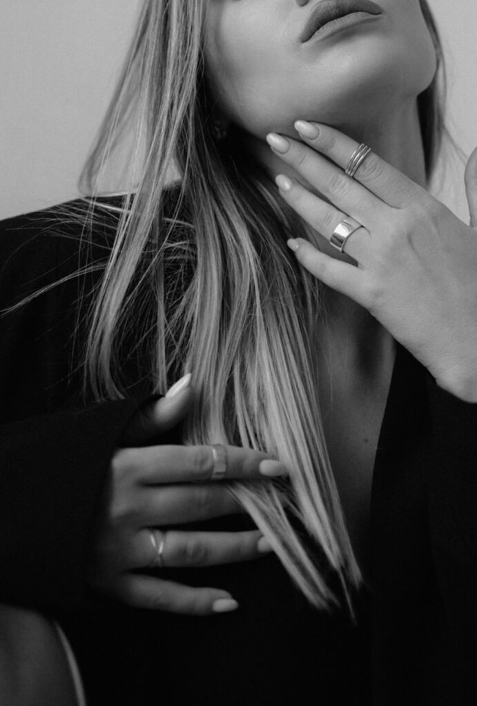 Vrouw met elegante, gemanicuurde handen bij haar hals en gezicht