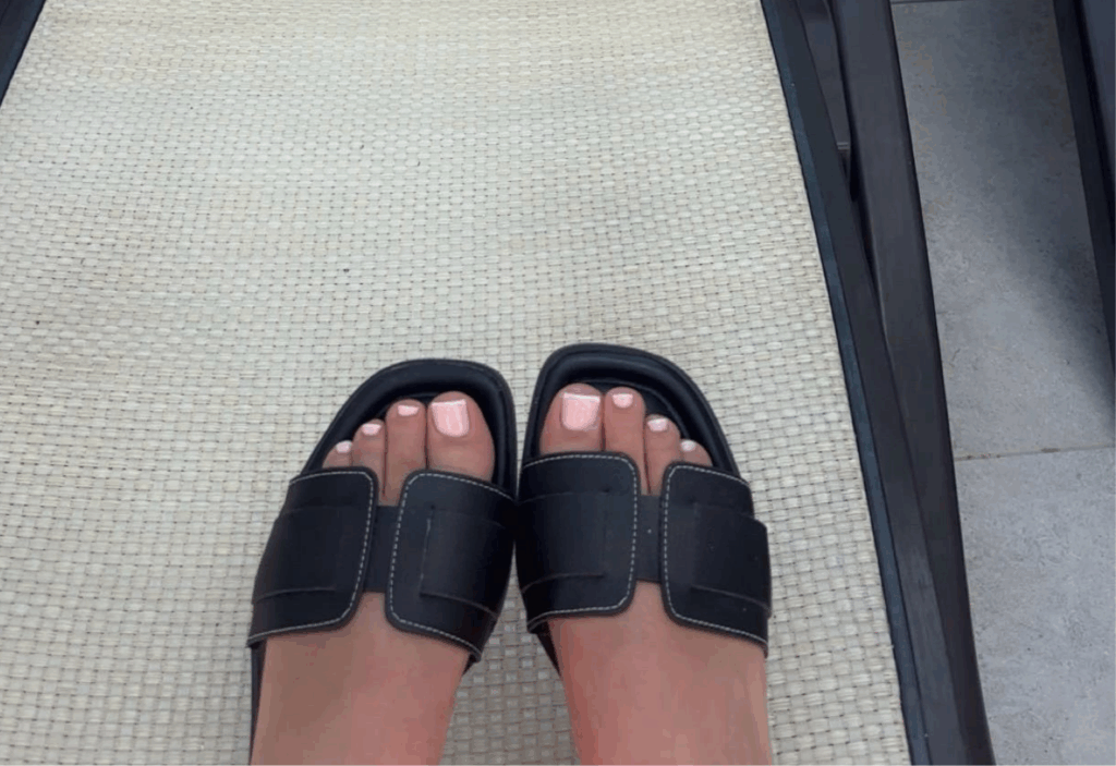 Net gepedicuurde voeten met frisse nagels in slippers